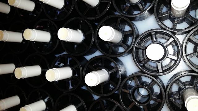 Lip balm in carriers on a conveyor line.